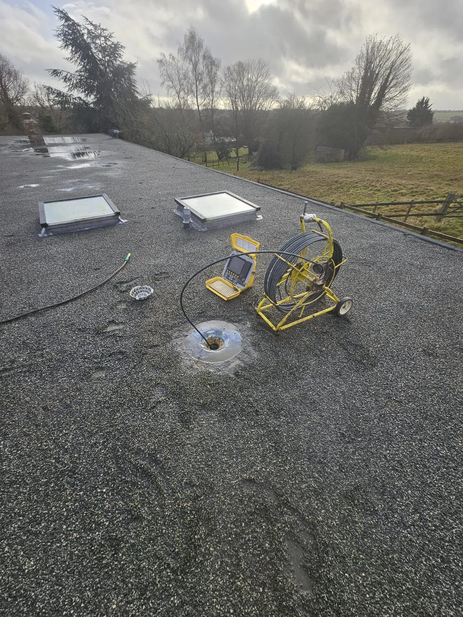 CCTV drain survey equipment set up on a flat roof, with the camera cable entering a roof drain to diagnose potential issues in Ipswich, Suffolk.